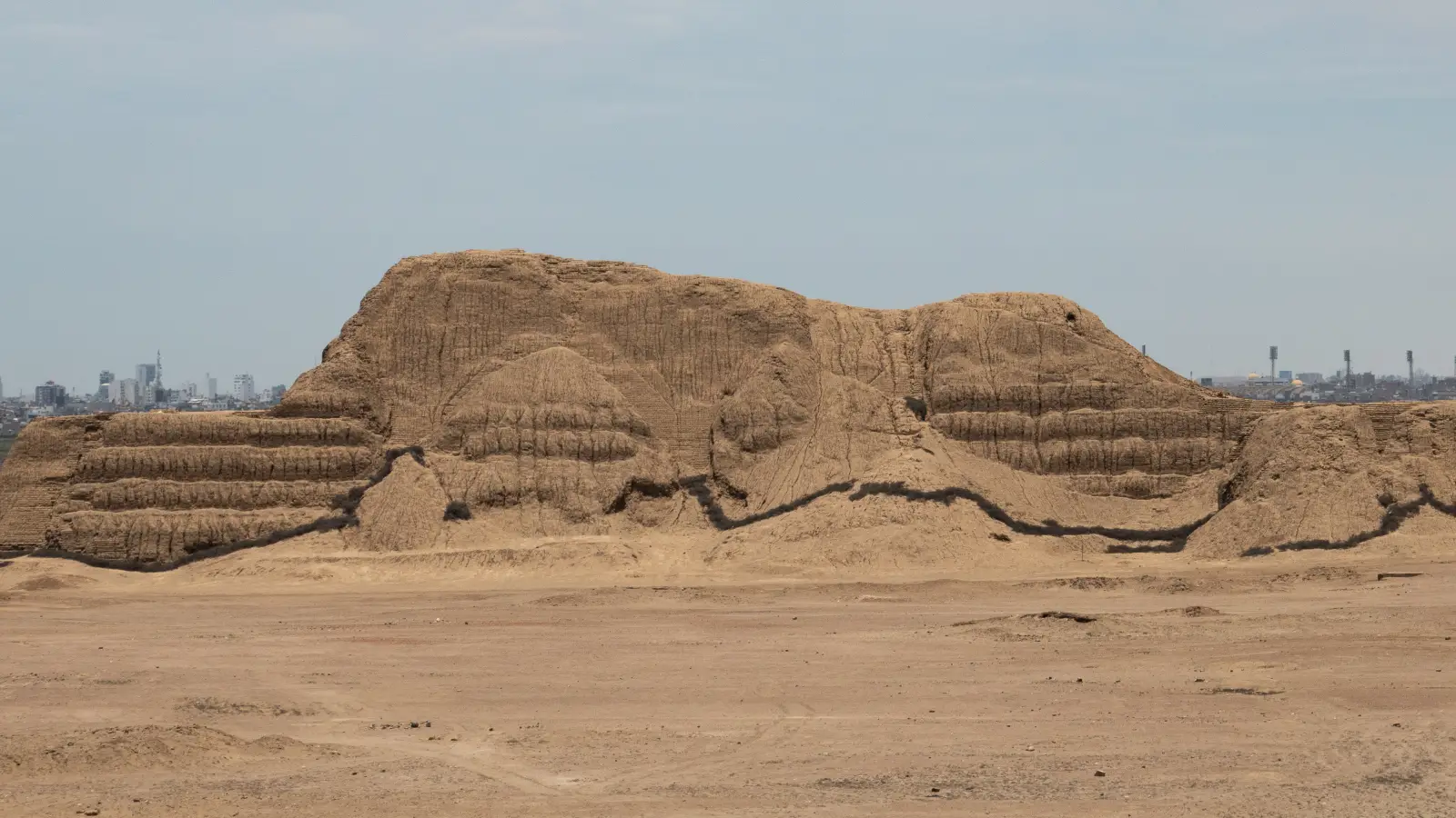 Eroded adobe mass of Huaca del Sol rising from the Moche Valley near Trujillo, Peru.