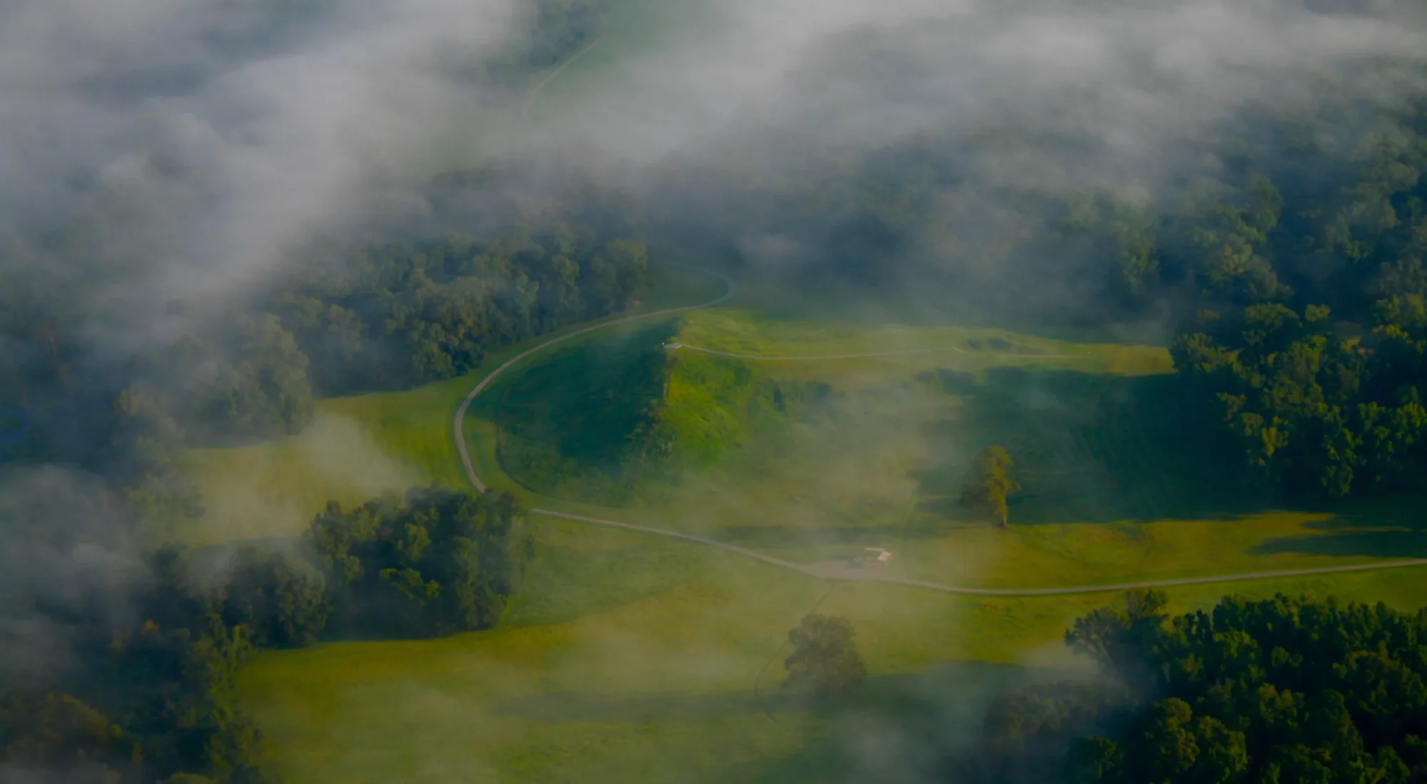 Aerial view through low cloud of Mound A and the green earthworks at Poverty Point