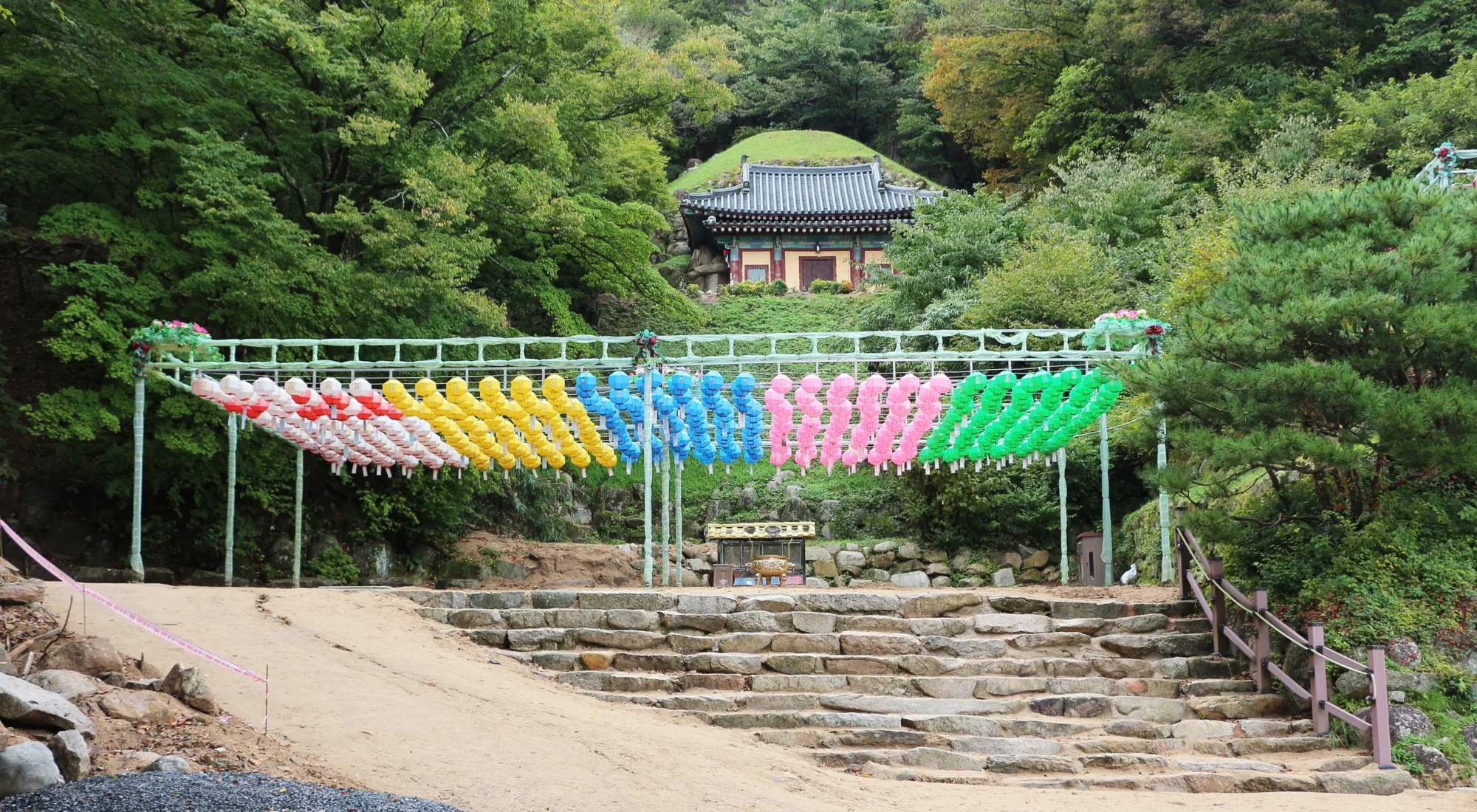 The entrance to Seokguram Grotto above stone steps and rows of colourful lanterns