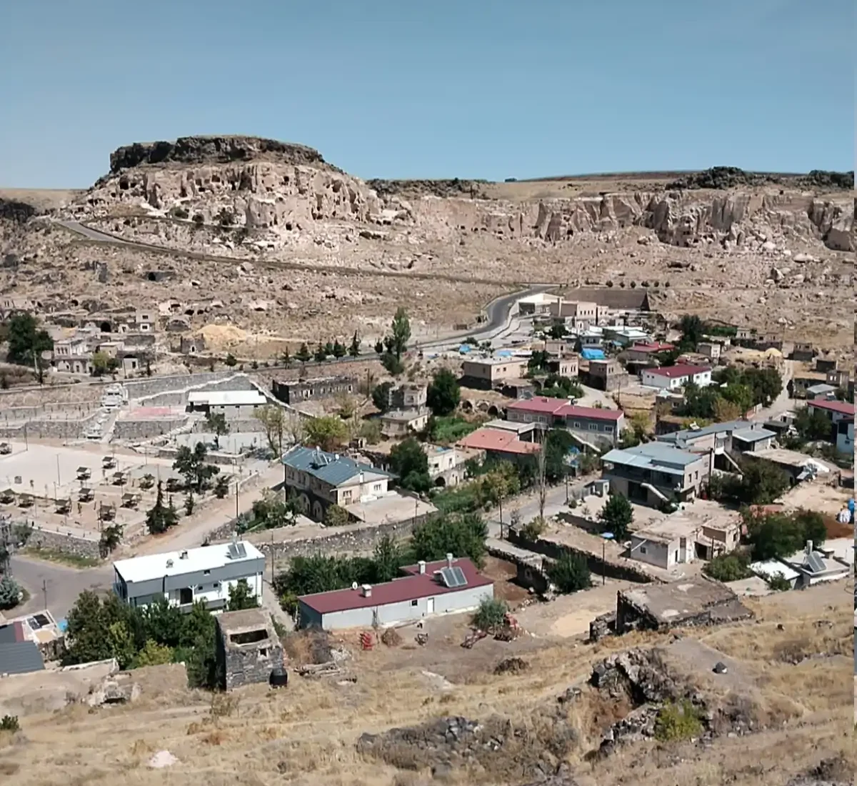 Tatlarin village and the rock-cut Cappadocian escarpment above it in central Turkey.