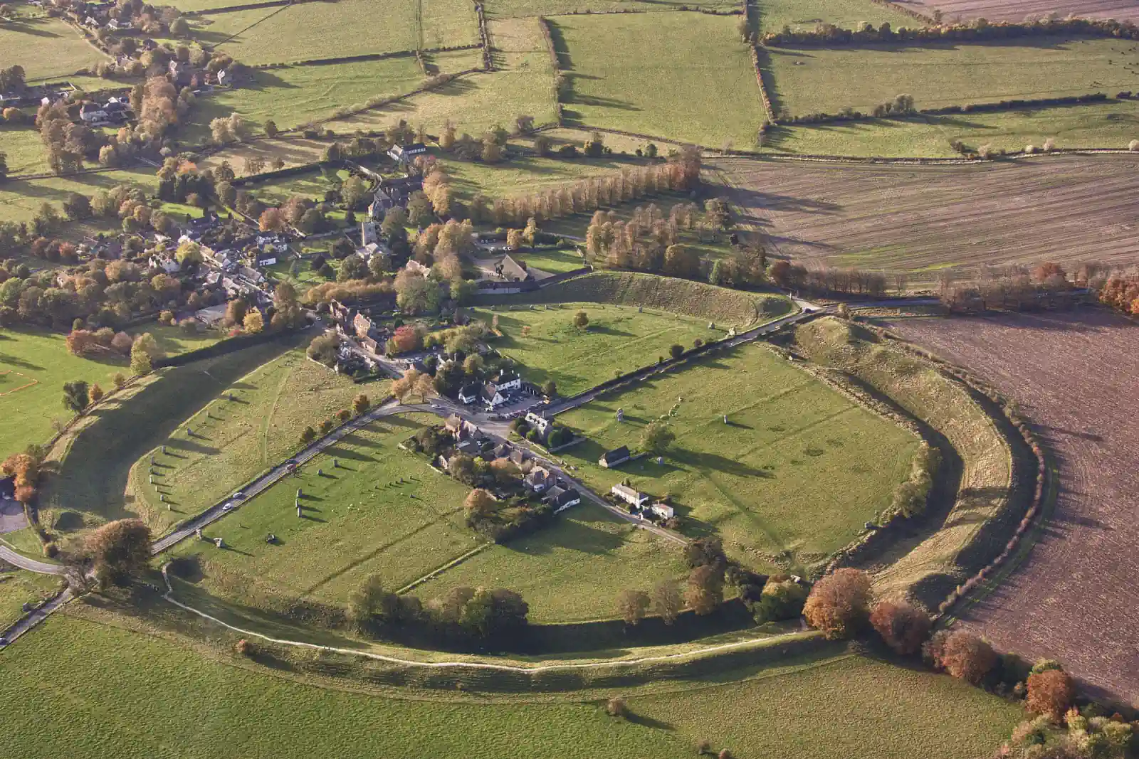 Aerial view of Avebury village, the prehistoric henge, and surviving stones within the Wiltshire landscape.