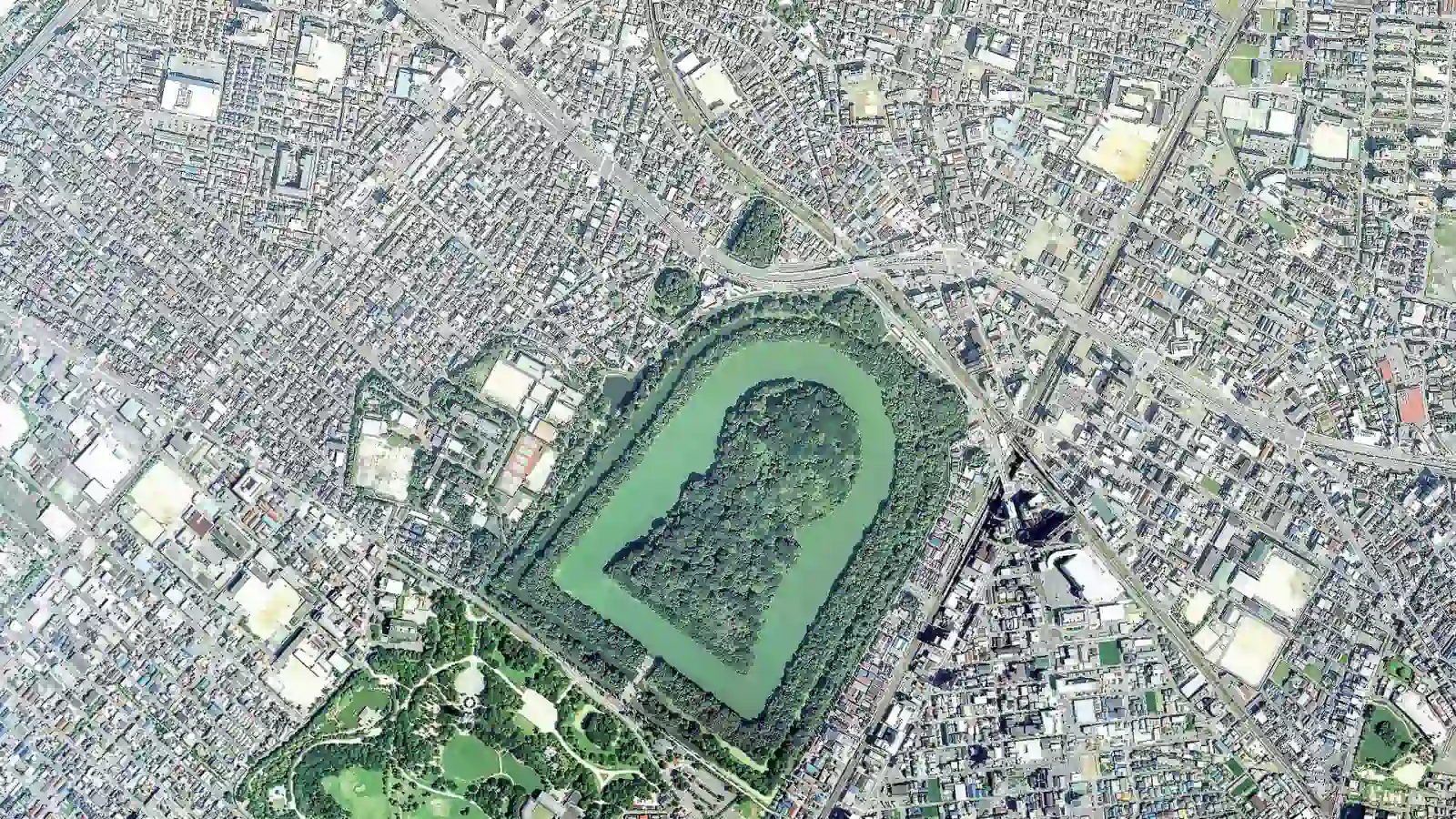 Aerial view of Daisen Kofun and its keyhole-shaped mound and moats within modern Sakai, Japan.